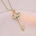 Elegant gold heart key necklace with green gemstone and zircon on pink satin background - Green