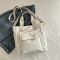 Minimalistische beige Tragetasche aus Nylon mit Fronttasche auf blauem Jeans-Hintergrund - Weiß