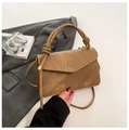 Dettaglio borsa vintage in pelle marrone opaca con manici annodati su sfondo di abito - Cachi