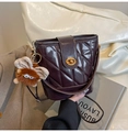 Details einer weinroten gesteppten Eimertasche mit goldenem Drehverschluss und Anhänger - Braun mit Anhänger