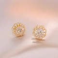 Set collana e orecchini a fiore dorato con zirconi su sfondo di raso champagne - Orecchini Rotanti Dorati