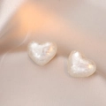 Eleganti orecchini a cuore con perle testurizzate su seta beige, vista angolata - Cuore Bianco Perla