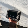 Borsa a tracolla leopardata con patta in pelle nera e catena dorata tenuta in mano - Nero (Leopardo Grigio)