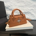 Bolso de mano minimalista en cuero marrón con estrella plateada sobre fondo de piedra - Marrón