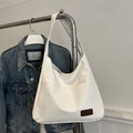 Large white faux leather tote bag with brown tag detail on casual denim background - White