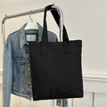 Minimalistische schwarze Canvas-Tasche mit dezenter Stickerei auf dichtem Stoff - Schwarz