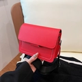 Red small square bag with a wide black adjustable shoulder strap and flap closure - Red