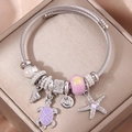 Dettaglio di un bracciale a treccia argento con ciondoli a tartaruga e stella marina su seta - Viola
