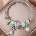 Silver twisted bangle with green heart and bear charms on champagne satin background - Light Green