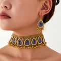 Detailed view of vintage gold choker and teardrop blue gem earrings on a model - Blue