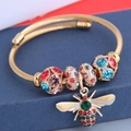 Detail of gold cable cuff bracelet with colorful rhinestones and honey bee charm - Colorful