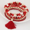 Detail von roten und goldenen mehrlagigen Boho-Perlenarmbändern mit einem Seidenquasten-Anhänger - Rot