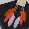 Macro detail of multi-color long feather earrings with orange, pink and purple plumes - White