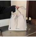 Primer plano del bolso tote de nailon crema con bordado azul y forro interior rosa - Blanco Roto