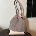 Borsa tote grigia in nylon con coulisse e fodera rosa appoggiata su libri d'arte - Grigio