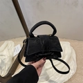 Detail of minimalist black crossbody bag with pleated texture and soft glossy finish - Black