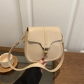 Bolso de hombro crema con cierre dorado sobre un fondo minimalista de madera - Caqui