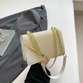 Beige crossbody bag with straw woven texture and gold chain strap in a stylish scene - White
