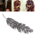 Detailed close-up of metallic feather hair clip with intricate carved textures in gold and silver - Silver