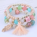 Close-up of bohemian multilayer bead bracelets with pink tassels and golden Hamsa Hand charms - Multicolor Hamsa Hand Style