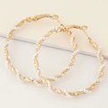 Golden twisted hoop earrings featuring white seed beads in a stylish spiral design - White