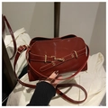 Détail d'un sac à main bordeaux en cuir verni avec boucle dorée et fini brillant - Rouge