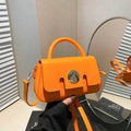 Vibrant orange leather handbag with large silver round buckle and adjustable strap - Orange