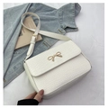 Détail du sac blanc à motif crocodile avec fermoir nœud doré sur fond en jean - Blanc Cassé