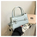 Detail of mint green handbag with bow buckle and silver hardware on white suitcase - Blue