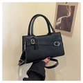 Close-up of black crossbody bag with decorative bow and silver buckles in hand - Black