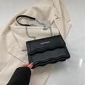 Bolso bandolera negro minimalista con solapa ondulada y correa de cadena metálica - Negro