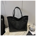 Dettaglio borsa tote in pelle intrecciata nera con rivetti dorati su tessuto bianco - Nero