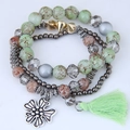 Dettaglio del bracciale multistrato bohémien con perline marmorizzate, fiore e nappa - Verde