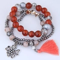 Detail view of multi-layer beaded bracelet with marble beads, cross charm and orange tassel - Orange