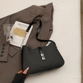 Schwarze gewebte Schultertasche mit Silberkette und Metallschnalle auf dunklem Blazer - Schwarz