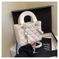 Dettaglio borsa bianca trapuntata con finiture dorate e manici circolari in pelle - Bianco con ciondolo