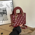 Close-up of wine red quilted handbag featuring shiny patent leather and golden hardware - Red