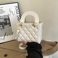 Detailed macro view of white quilted leather texture and shiny golden hardware buckles - White