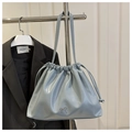 Close-up of drawstring shoulder bag with glossy light blue finish and silver bow detail - Blue