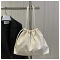 Close-up of cream pleated tote bag with metal bow detail and drawstring closure - White