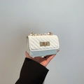 Mini white quilted crossbody bag with gold hardware and chain strap held by hand - White