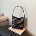 Minimalistische schwarze Handtasche mit elfenbeinfarbenen Schleifen auf einem Buch - Schwarz