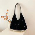 Black velvet hobo tote bag with gold stud rivets and leather handle shown in warm setting - Black