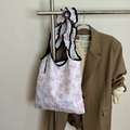 Bolsa de compras plegable con estampado floral rosa y detalles de volantes negros en el asa - Flor Blanca