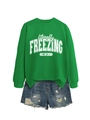 Detailed flat lay of a green crewneck sweatshirt with freezing print and ripped denim shorts - Grass Green Sweatshirt (White Pattern) / S