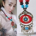 Detail of ethnic necklace with red beads, blue stones, and bronze floral tassel charms - Red Flower
