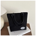 Primer plano del bolso tote de pana negra con etiqueta de la marca FANYISSA cosida - Negro