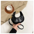 Detalle de un bolso de media luna negro con herrajes dorados y textura de cuero fino - Negro