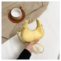 Detalle de bolso medialuna de cuero amarillo con cierre metálico dorado y costuras finas - Amarillo
