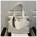 Detail of off-white tote bag with black drawstring, metal snap, and tennis racket charm - With Charm / White
